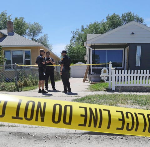 Police officers stand in front of the home,...