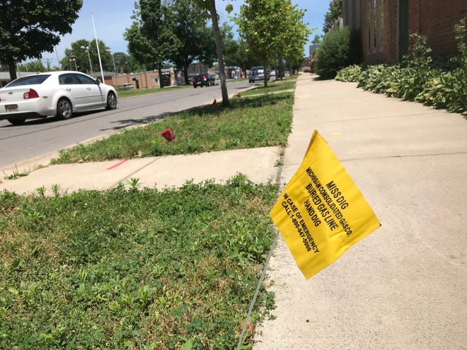 A Miss Dig warning flag — yellow for natural gas — marks a buried pipe under a sidewalk on Mack Avenue in Grosse Pointe Farms on Sunday.