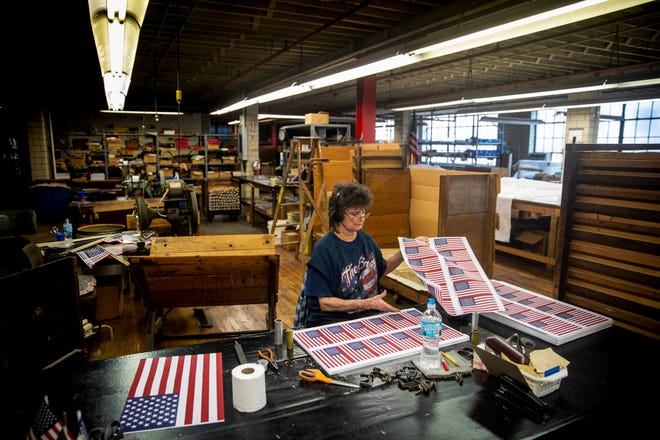 Donna Barnes stacks sheets of mini American flags at The National Flag Company in the West End Tuesday, July 2, 2019. Barnes has worked at The National Flag Company for 32 years. 