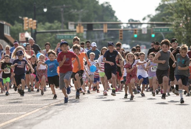 Kids sprint down Main Street in downtown Brighton for the Duckling Dash, which was led by a pace vehicle driven by the race's mascot as part of Brighton's Independence Day festivities races on Thursday, July 4, 2019.