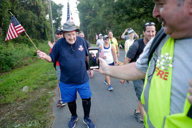 Ernie Andrus, a World War II veteran who is walking across the United States for a second time while in his nineties, smiles and waves an American flag as he is broadcasted on a Facebook live video July 4, 2019. 