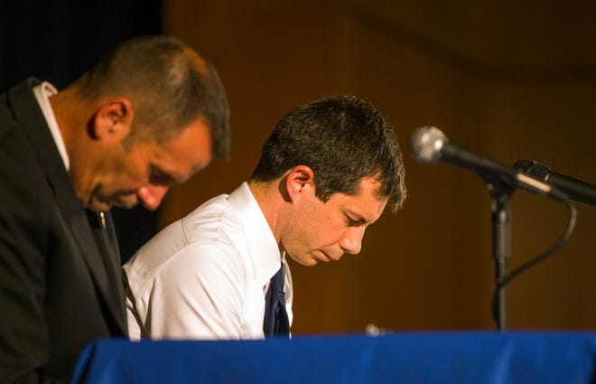 In this June 23, 2019 photo, Democratic presidential candidate and South Bend Mayor Pete Buttigieg, right, and South Bend Police Chief Scott Ruszkowski, left, bow their heads in prayer during a town hall community meeting at Washington High School in South Bend, Ind.