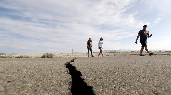 Visitors cross highway 178 next to a crack left...