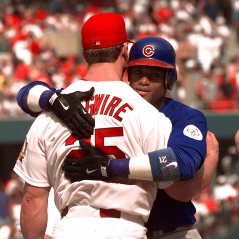 Mark McGwire gets a hug from Sammy Sosa, right, in