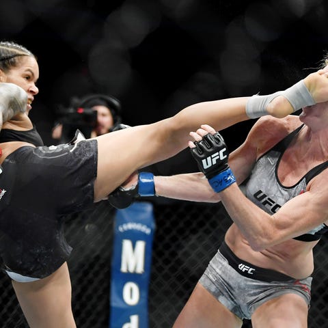 Amanda Nunes (red gloves) fights Holly Holm (blue...