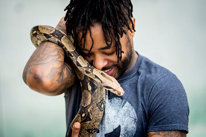 Ari White holds his snake Bam Bam, a red-tailed boa constrictor.
