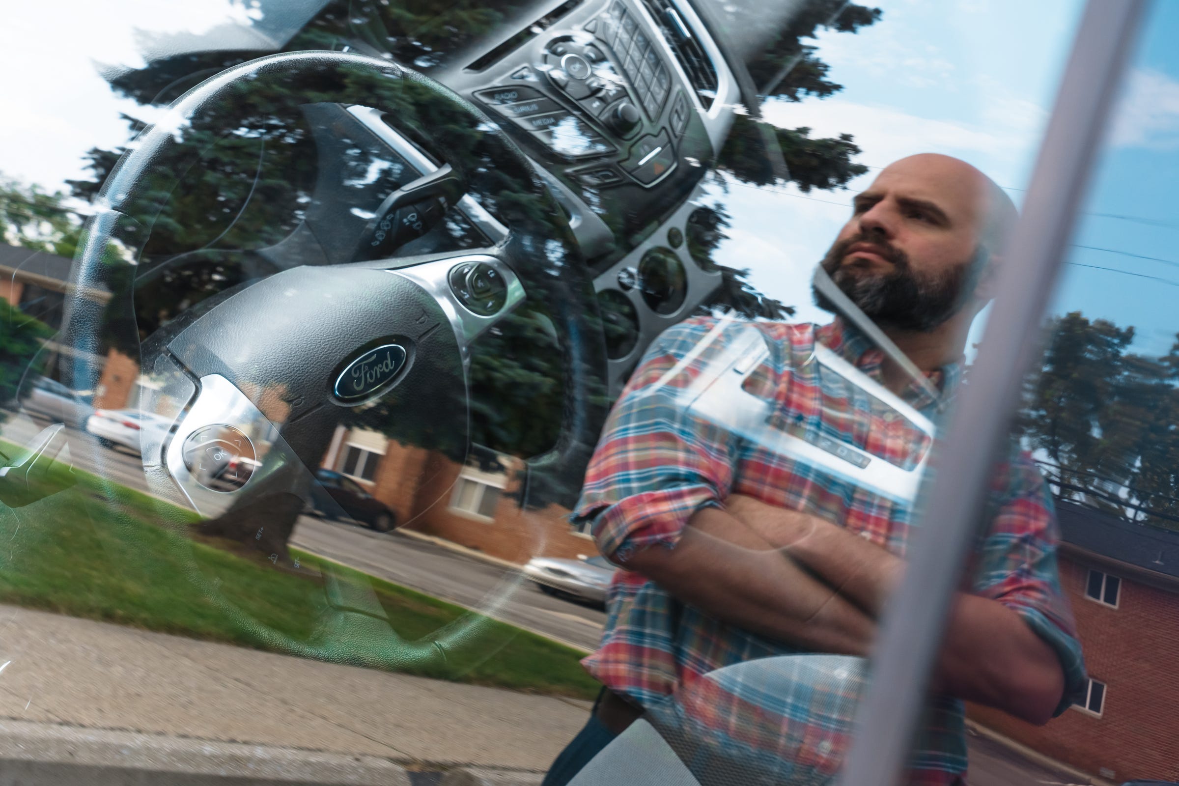 Ryan Karczewski is reflected in the driver's side window of his 2014 Ford Focus SE outside of his apartment in Royal Oak on Friday, June 28, 2019.