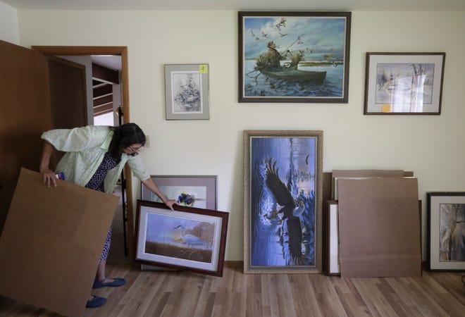 Susan de Wit organizes a variety of paintings Monday at her late parents' home in Menasha. DeWitt, a Fox Cities native, is holding a weekend art exhibit and sale.