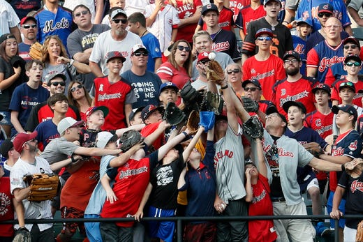 Fans battle for a home run ball during batting practice for the MLB All-Star baseball game, July 8, 2019, in Cleveland.