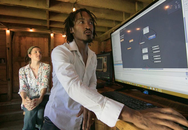 Elijah Hamilton shows the basic programming flow of a simple movement of an animated video character Thursday, July 11, 2019 with wife and partner Erin Hamilton in a barn on their farm in Howell. The couple founded Mitten Pixels, a game design and development company.