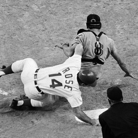 Pete Rose slams into catcher Ray Fosse as he...