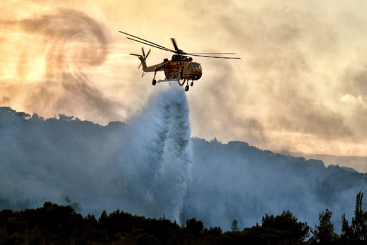 A helicopter tries to extinguish the wildfire outside of Corinth, Greece on July 10, 2019. 64 firefighters, 24 land vehicles, 3 aircraft, 3 helicopters and 2 water wagons battled the fire.