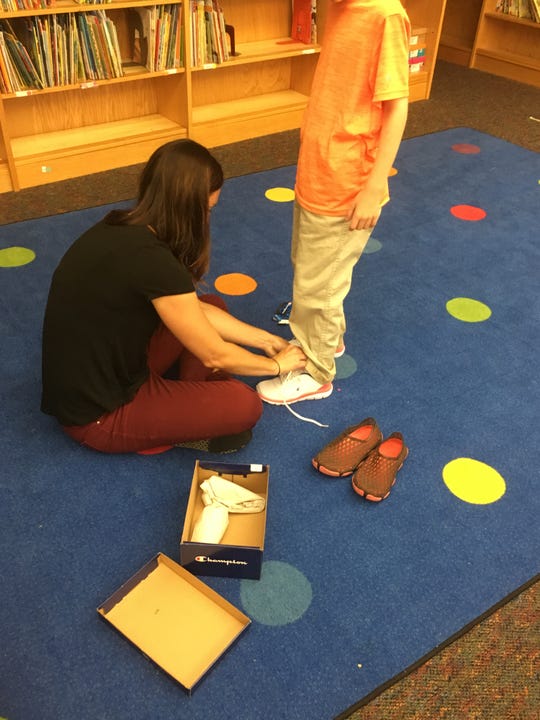 Ashley Knuth ties a pair of new shoes donated through New Kicks for Kids in spring 2019.