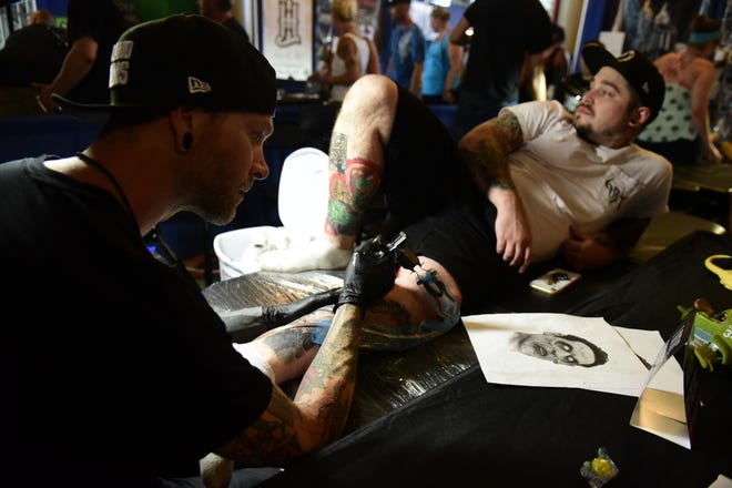 Nick Daugherty, left, takes a look at the drawing he tattooed on Levi Kline during the 2019 INKcarceration music festival.