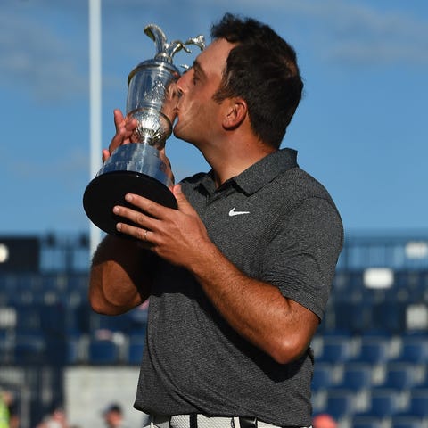 Francesco Molinari kisses the trophy as he poses...