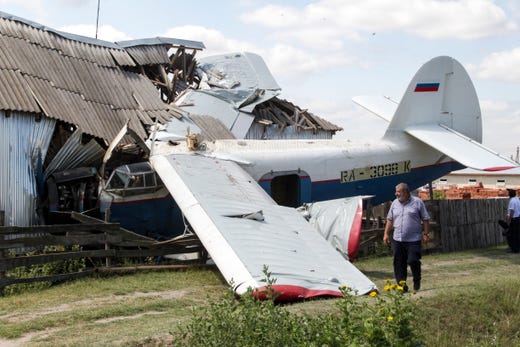 A man walks at the scene of a small private plane An-2 that crashed into house in Novoshchedrinskaya, Russia on July 16, 2019.