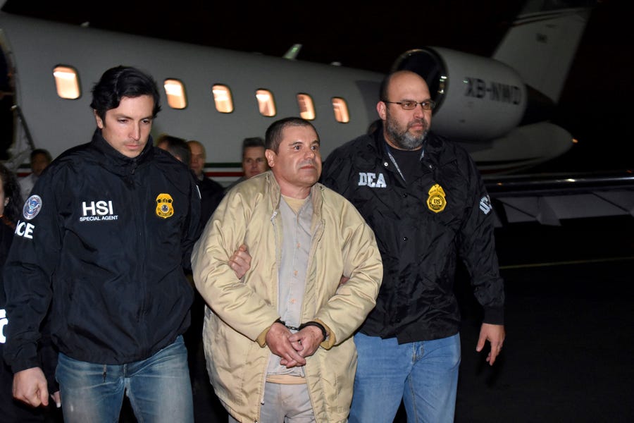 Authorities escort Joaquin "El Chapo" Guzman from a plane to a waiting caravan of SUVs at Long Island MacArthur Airport, in Ronkonkoma, N.Y. Guzman, who was convicted in February 2019 on multiple conspiracy counts in an epic drug-trafficking case, will be sentenced in a New York courtroom on July 17, 2019.
