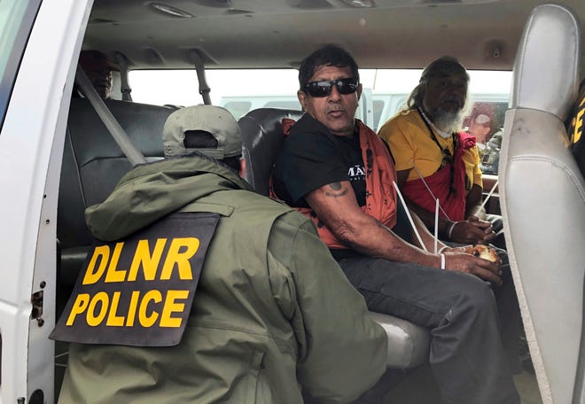 Officers from the Hawaii Department of Land and Natural Resources arrest protesters, many of them elderly, who are blocking a road to prevent construction of a giant telescope on a mountain that some Native Hawaiians consider sacred.