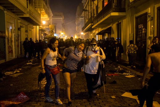 Demonstrators affected by tear gas thrown by the police run during clashes in San Juan, Puerto Rico, July 17, 2019. Thousands of people marched to the governor's residence in San Juan on Wednesday chanting demands for Gov. Ricardo Rossello to resign after the leak of online chats that show him making misogynistic slurs and mocking his constituents.