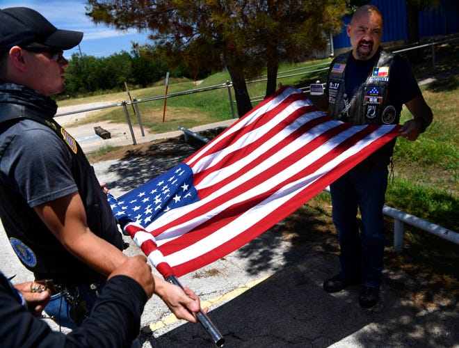 Nathaniel Gallion, (left) and Dennis Kuhn, both of Abilene, roll up the Nation of Patriots flag before taking it to the Dallas-Fort Worth area on Wednesday. The group of about 10 riders met at American Legion Post 57 and escorted the flag east to American Legion Post 453