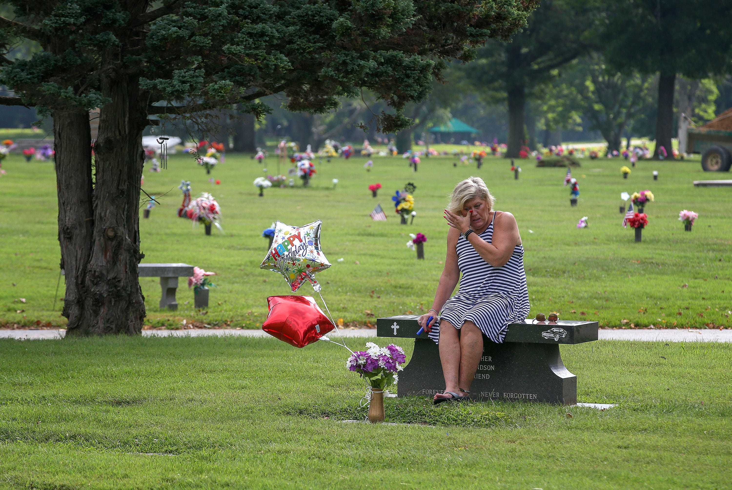 Michele Crockett, mother of Max Gilpin, visits at the grave of her son. It would have been Max Gilpin's 26th birthday, and she brought balloons as she does every year. He died after becoming overheated at football practice at Pleasure Ridge Park High School in 2008.
July 19, 2019