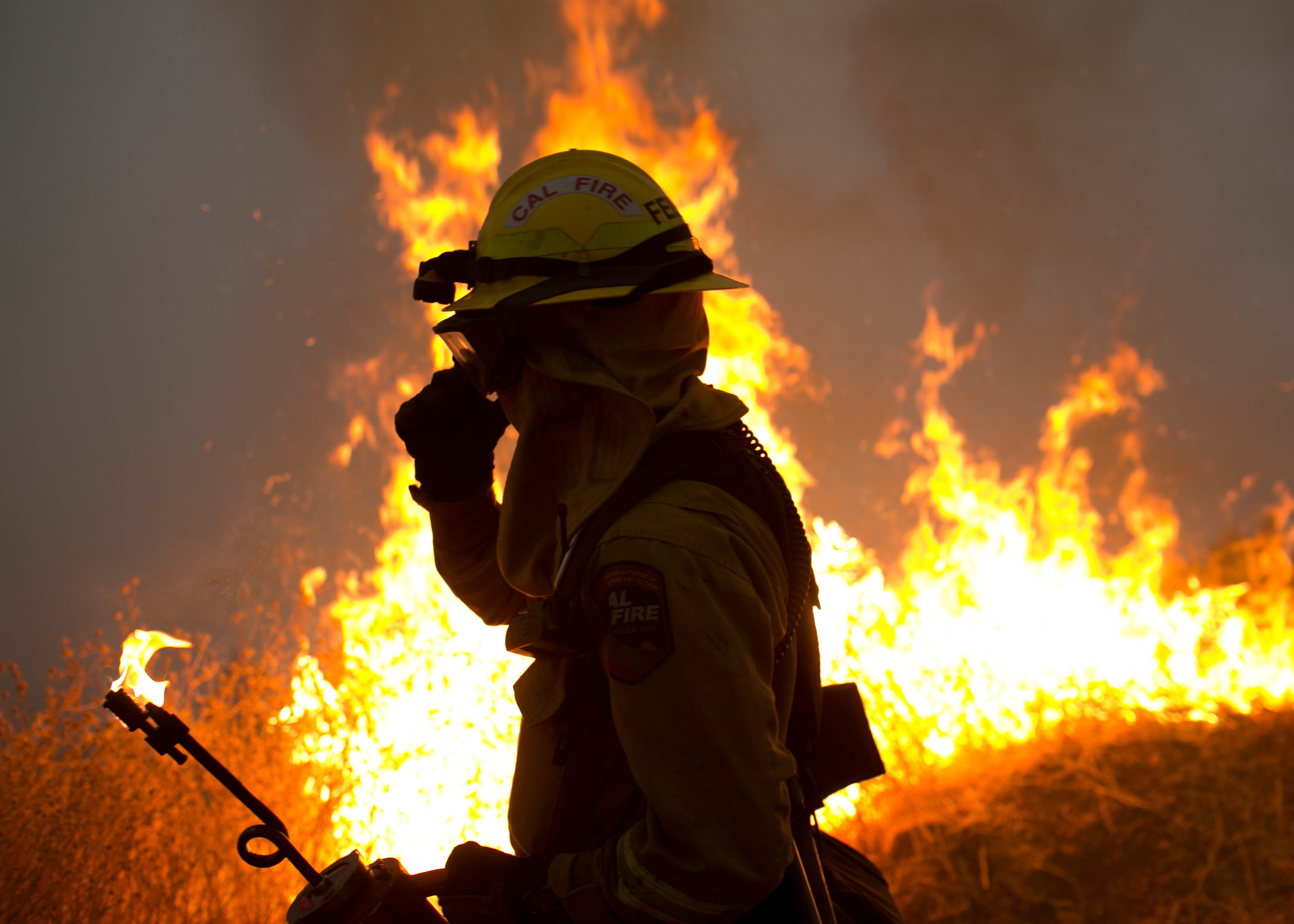 A firefighter helps ignite a controlled burn in an attempt to halt the Camp Fire on Nov. 14, 2018.