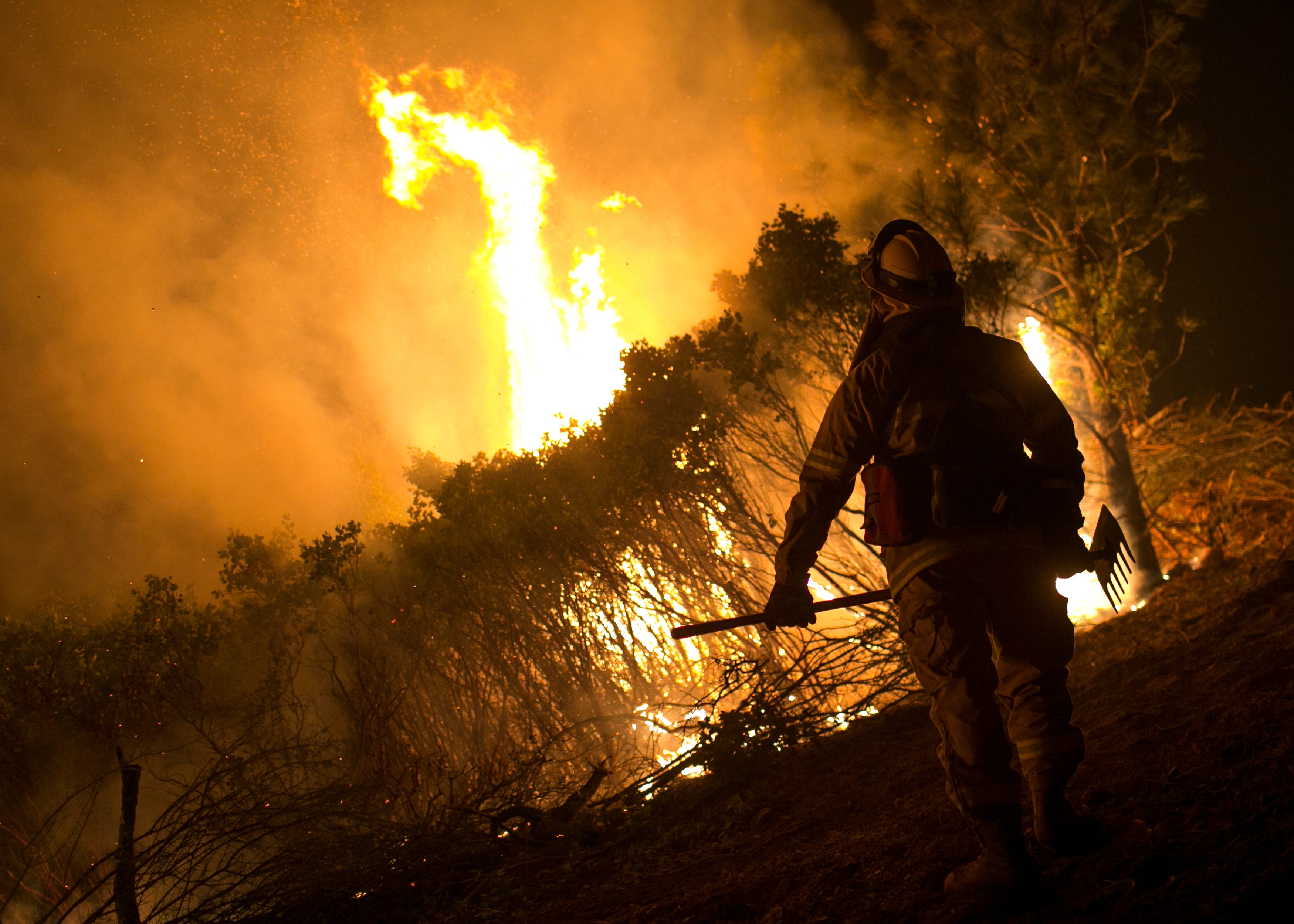 A firefighter with Cal Fire stands watch in front of a control burn used to fight the Camp Fire near Bloomer Hill in Butte County in California on Wednesday, Nov. 14. 2018. 