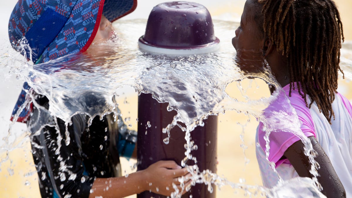 Children put their faces in a fountain at a water park during an excessive heat watch in Washington, on July 19, 2019. An excessive heat watch has been issued for the weekend in Washington DC.