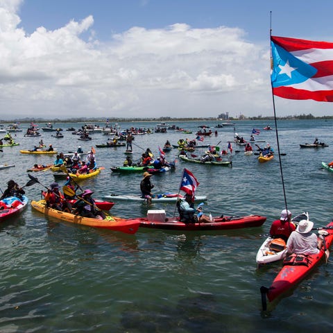 Demonstrators in kayaks gather in front of La...
