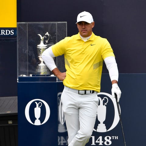 Brooks Koepka stands in front of the Claret Jug...