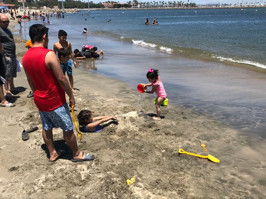 Alis Zuniga pours a bucket of seawater on her half-buried friend at Cabrillo Beach in the San Pedro section of Los Angeles. Though it is clean most days, the beach can have high bacteria counts at certain times of year.