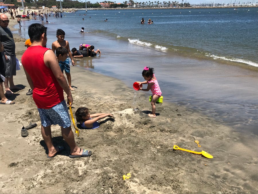 Alis Zuniga pours a bucket of seawater on her half-buried friend at Cabrillo Beach in the San Pedro section of Los Angeles. Though it is clean most days,  the beach can have high bacteria counts at certain times of year.
