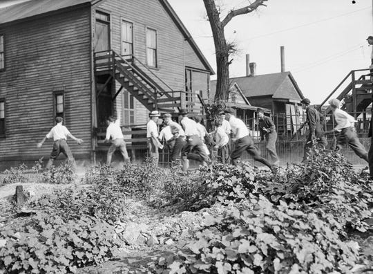 In this 1919 photo provided by the Chicago History Museum, a victim is stoned and bludgeoned under a corner of a house during the race riots in Chicago.