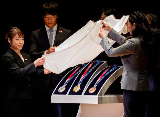 Olympic medalists unveil the Tokyo Olympics medals (L-R; Silver, Gold and Bronze) during the One Year to Go Ceremony at Tokyo Forum in Tokyo, Japan, 24 July 2019.