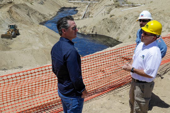 Gov. Gavin Newsom, left, is briefed by a Chevron official and California oil regulator last July while touring a massive oil spill. (Irfan Khan/Los Angeles Times via AP, Pool)