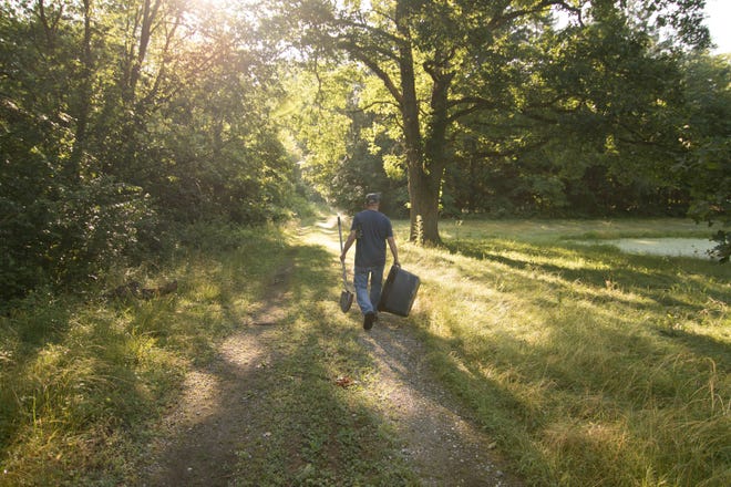 In this July 24, 2019, photo a pet owner walks a path to the area of Heavenly Acres Pet Cemetery where his dog Henry is buried in Genoa Township.