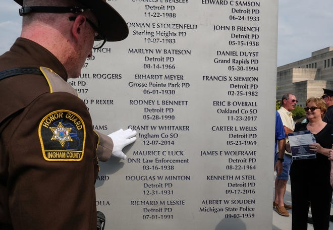 Ingham County Sheriff Deputy Matt Hutting touches the name of Grant W. Whitaker who died in the line of duty in December 2014 at the Michigan Law Enforcement Officers Memorial Monument Dedication and Memorial Service Saturday, July 27, 2019 in Lansing, Michigan.