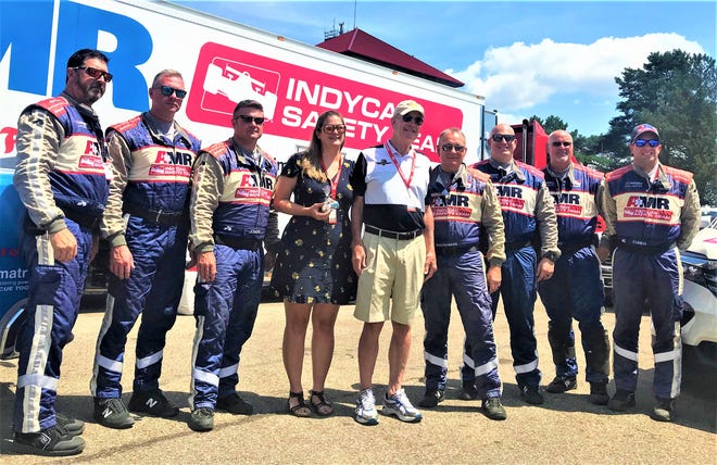 Gerry Schroeder, center, and his daughter, Kathryn, pose with members of the AMR Safety team who saved Gerry's life last year when he collapsed in pit lane due to cardiac arrest at the Honda Indy 200 at Mid-Ohio. In 2019, he made his return to Mid-Ohio to express his gratitude.