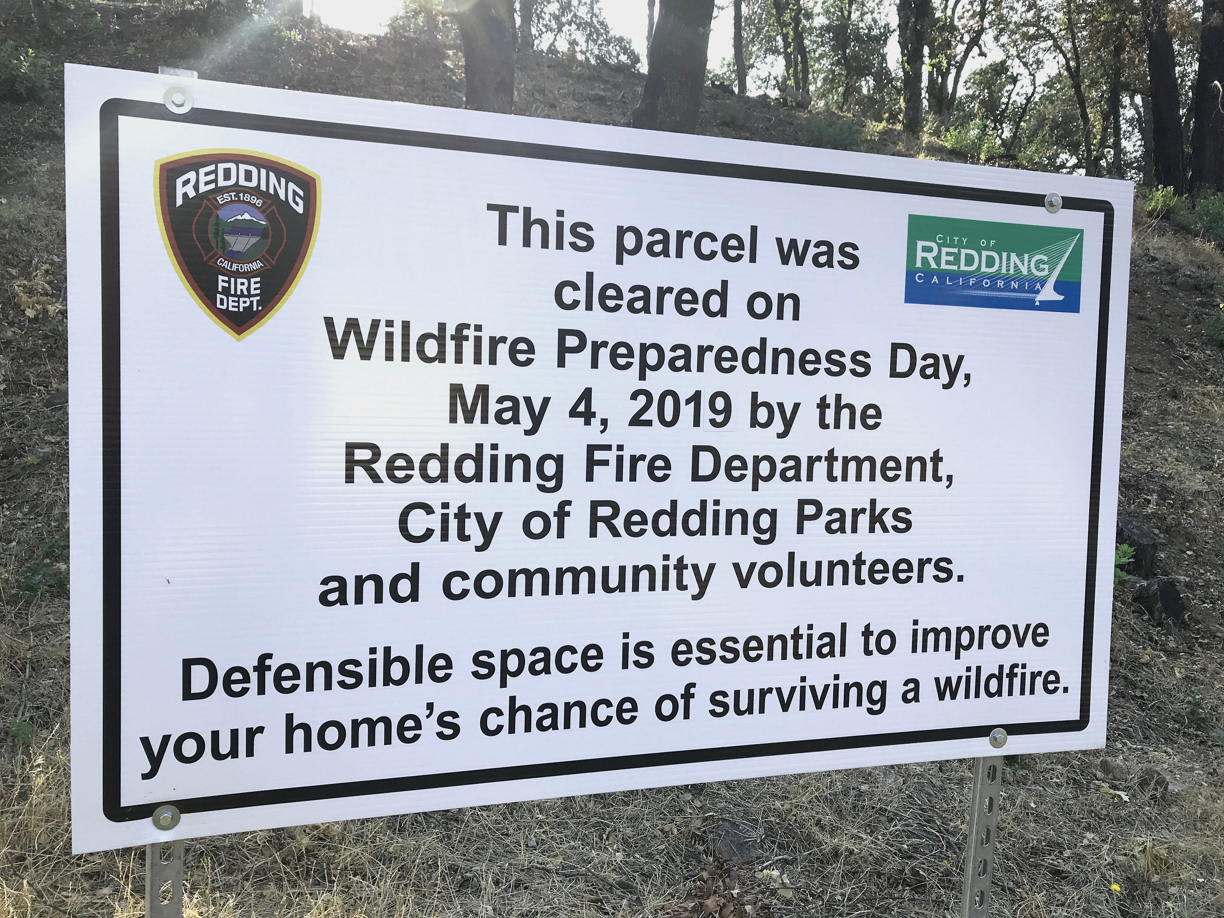 A Redding Fire Department sign on a hillside off Blazingwood Drive in Country Heights points out the defensible space work done in the spring. The other side of the street, however, remained uncleared months later.