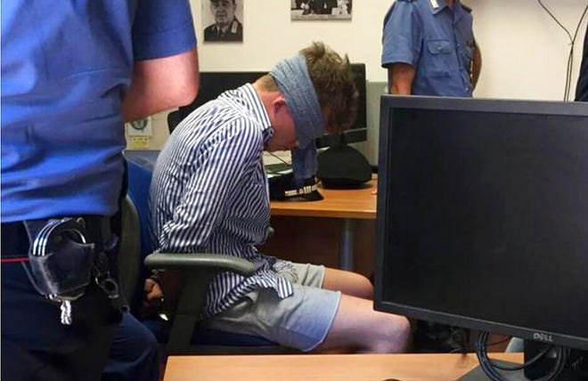 In this photo obtained from Italian Carabinieri, Gabriel Christian Natale-Hjorth sits blindfolded in a police station in Rome on Friday July 26, 2019.