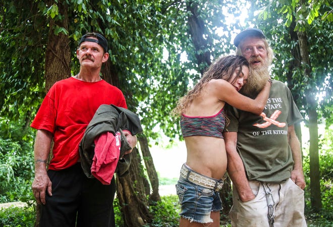 Amanda Bradshaw hugs boyfriend David Walston as they watch along with friend Gary Reed the home the couple built out of discarded lumber and pallets gets demolished Monday afternoon. The trio with three others were living in the woods along the banks of Silver Creek in New Albany before the city ordered the camp to be removed. July 29, 2019