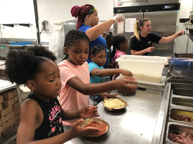 Tiphani Jackson, 8,  at left, Jaylin Luttrell, 7, and Kamani Phillips, 8, learned to make their own pizzas Monday at Gionino's Pizzeria on West Fourth Street during the UMADAOP Summer Camp as employees of the business help them with their orders.