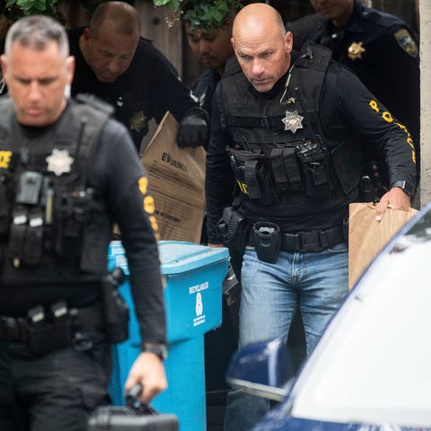 Police officers carry evidence bags from the...