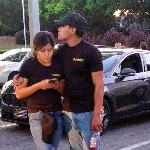 A young couple embrace at a parking lot after a...