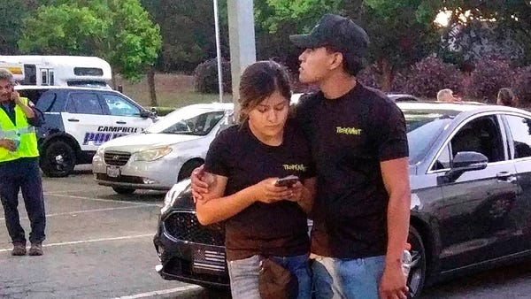 A young couple embrace at a parking lot after a...