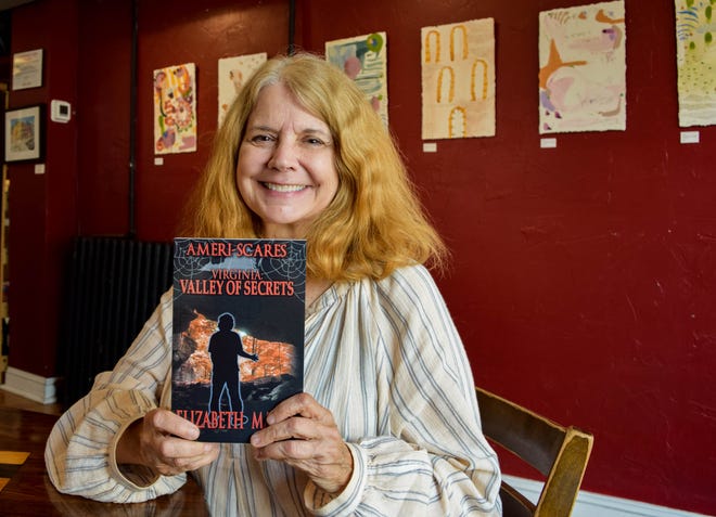 Local author Elizabeth Massie poses with one of her "Ameri-Scares" books on Tuesday, July 30, 2019. Massie is in the process of writing 50 books for the series, one for each state, based on folk tales, legends and historical events. She is currently writing the 10th book in the series.