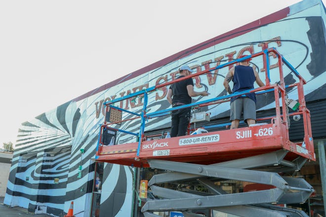 Matthew Mederer and Max Komarov paint "Whoopsie Daisy" on the Voline service station in Wauwatosa in 2019 as part of the North Avenue Mural Arts District. Wallpapered City, the artist-led group that implemented the Tosa project, is spearheading a similar project in West Allis, which will install murals on several buildings along Greenfield Avenue.