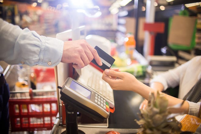 A customer handing a credit card to a cashier at a grocery store.