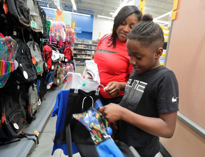 Carolyn Harris helps Nyzer Pendleton, 10, buy a backpack for school Friday at the Super Walmart in Greendale. He chose a Teenage Mutant Ninja Turtles backpack for when he starts school in Milwaukee in the fall.