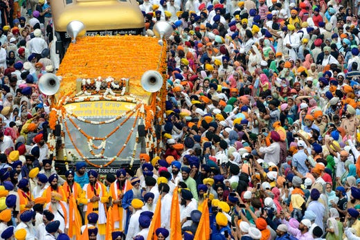 Sikh devotees gather around a bus carrying the Guru Granth Sahib, a Sikh holy book, during the 'Nagar Kirtan' procession to mark the 550th birth anniversary of Guru Nanak Dev, the founder of Sikhism, near the Golden Temple in Amritsar on August 2, 2019.
